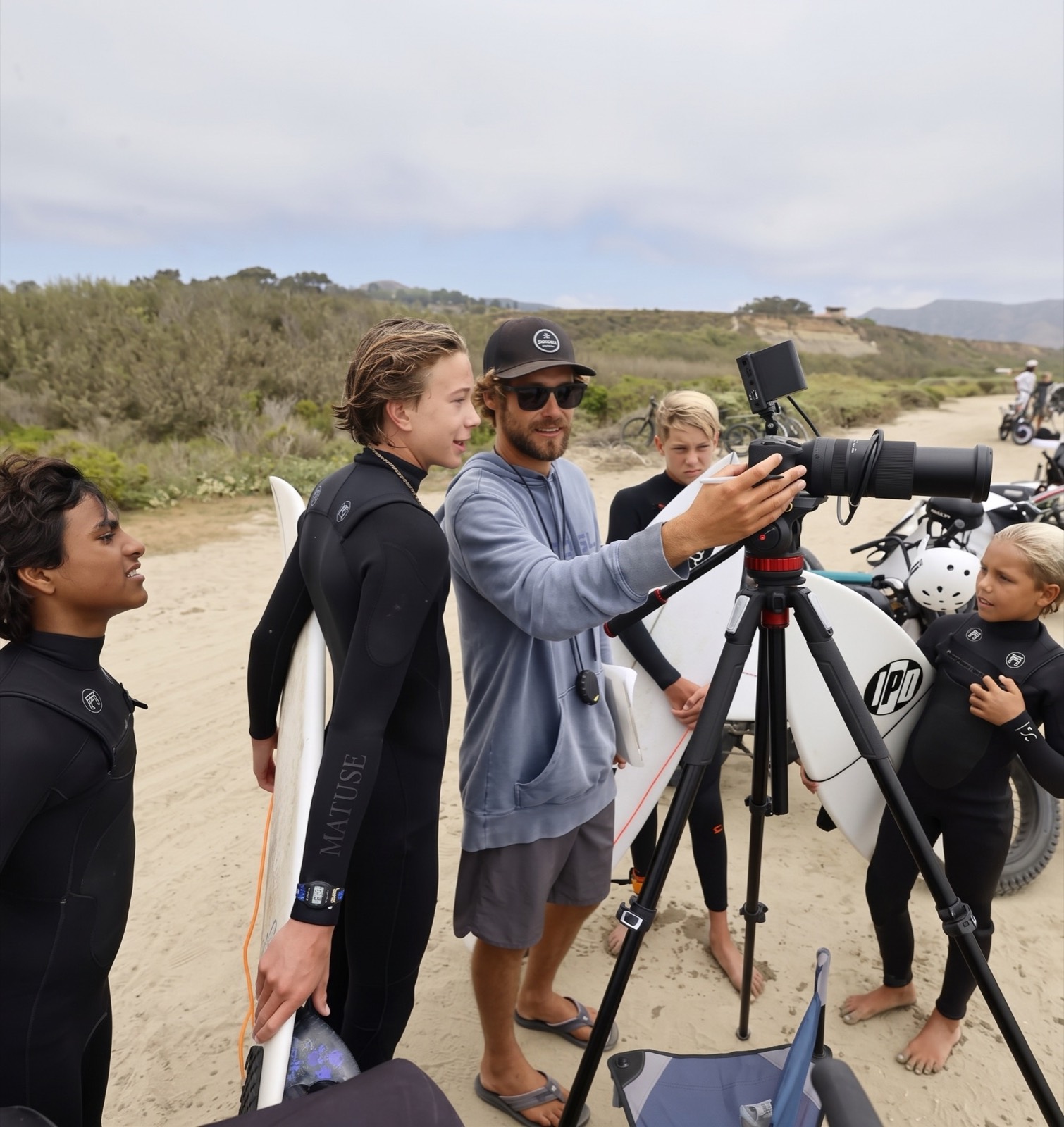 Lucas reviewing footage with young surfers around a camera on a tripod