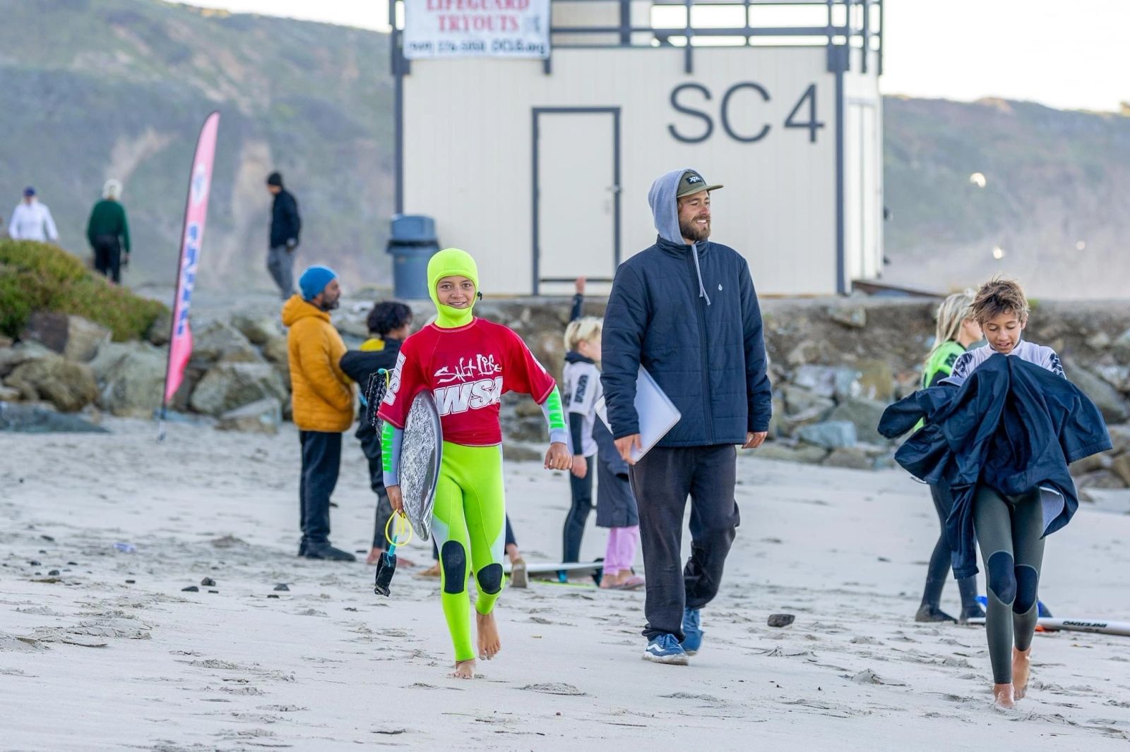 Surfer with coaches on the beach in winter
