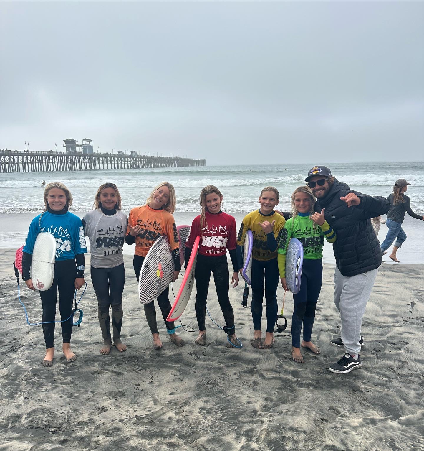 Lucas with a team of young girls in contest jerseys at the Oceanside pier