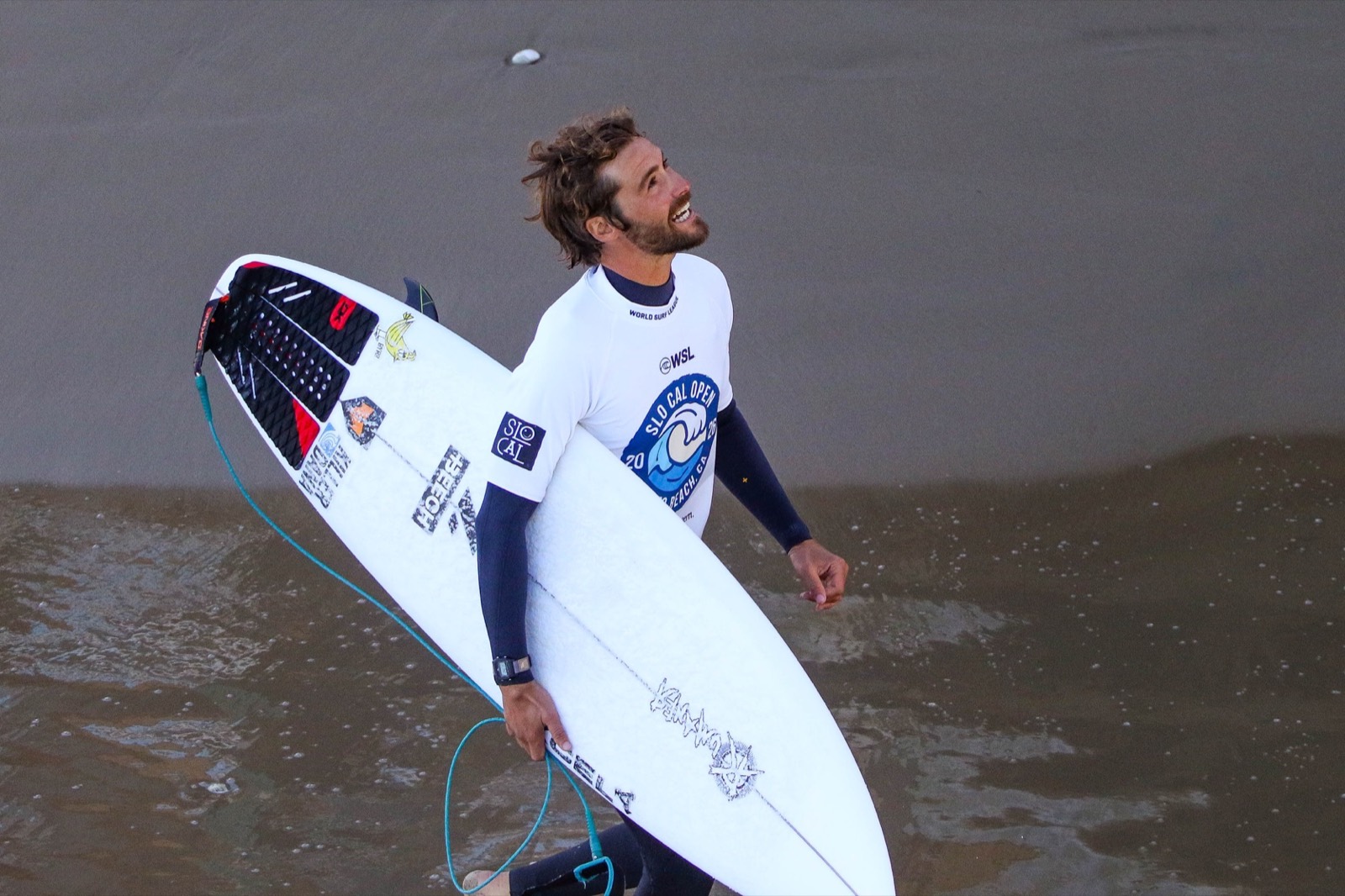 Lucas Taub in his contest jersey carrying his board at a WSL Qualifying Series event