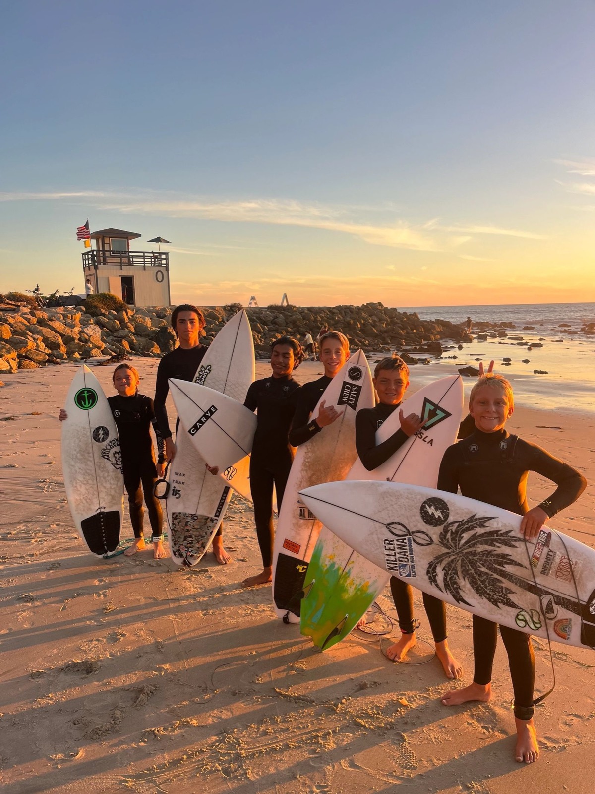DP Surfcoach groms together on the beach at sunset with their boards